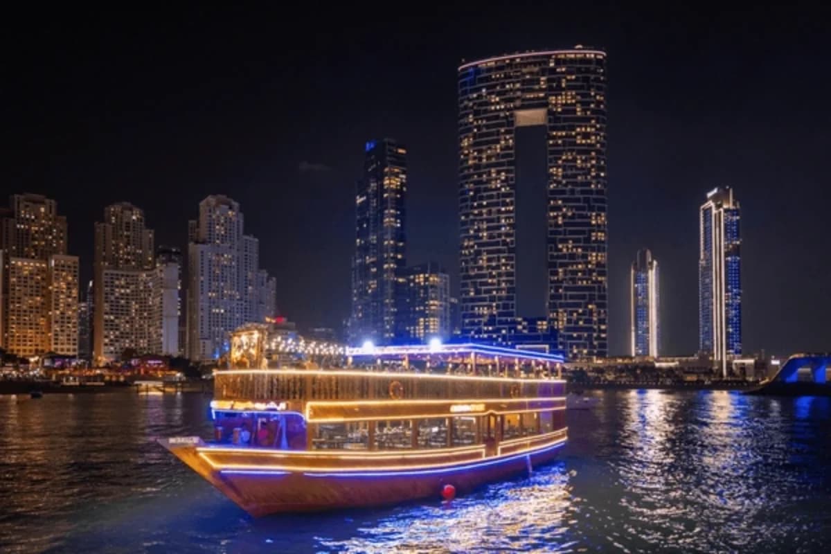 A traditional dhow boat illuminated at night in Dubai Creek.