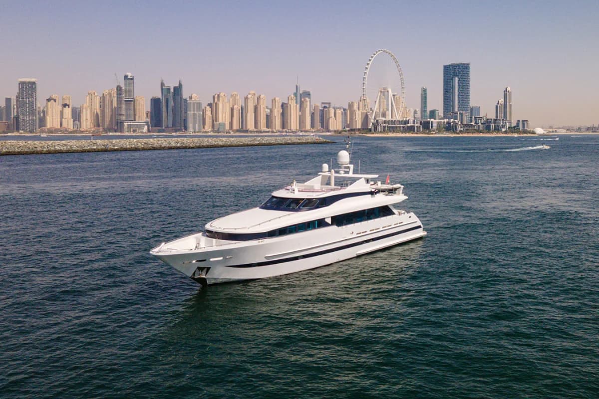 A luxury yacht cruising through Dubai Marina with skyscrapers in the background.